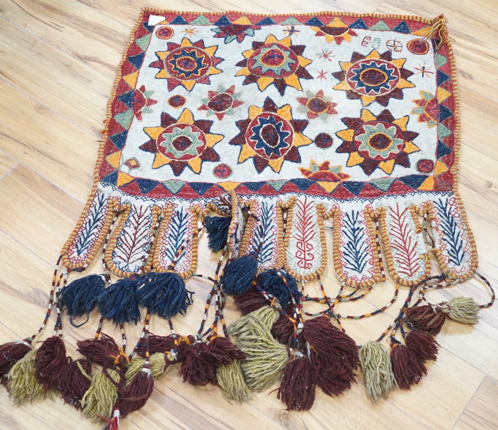 An African tribal bead and shell work necklace together with an embroidered Uzbek saddle bag with tassels and a similar felt wall hanging, the largest 110cm x 82cm